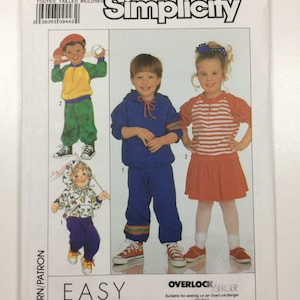 May include: Simplicity sewing pattern number 9324 for children's clothing. The pattern includes instructions for making a red and white striped shirt, a blue sweatshirt, and a pair of blue pants. The pattern is labeled "Easy to Sew" and "Overlock/Serger".