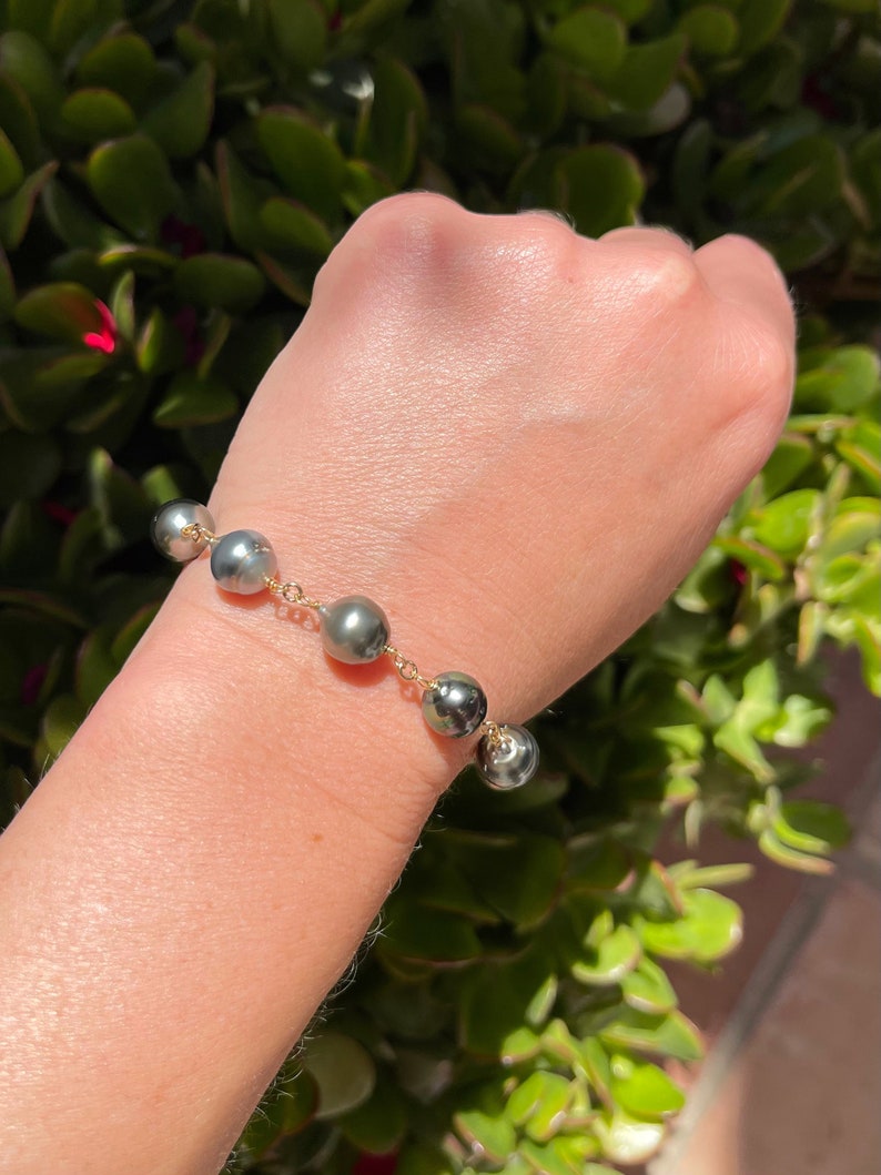 May include: A bracelet with a gold chain and dark gray pearls.