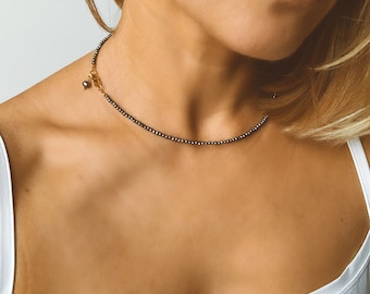 May include: A delicate silver necklace with a small pearl pendant. The necklace is made of tiny beads and has a simple, elegant design.