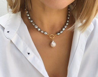 May include: A silver pearl necklace with a large white pearl pendant and a gold clasp.