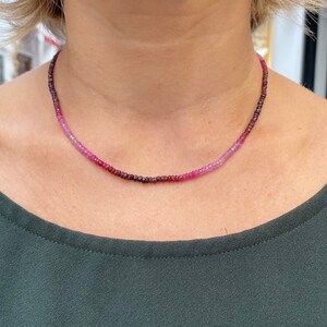 May include: A delicate necklace made of small, graduated pink and purple gemstones. The necklace is made of tiny beads that are strung together to create a gradient effect.