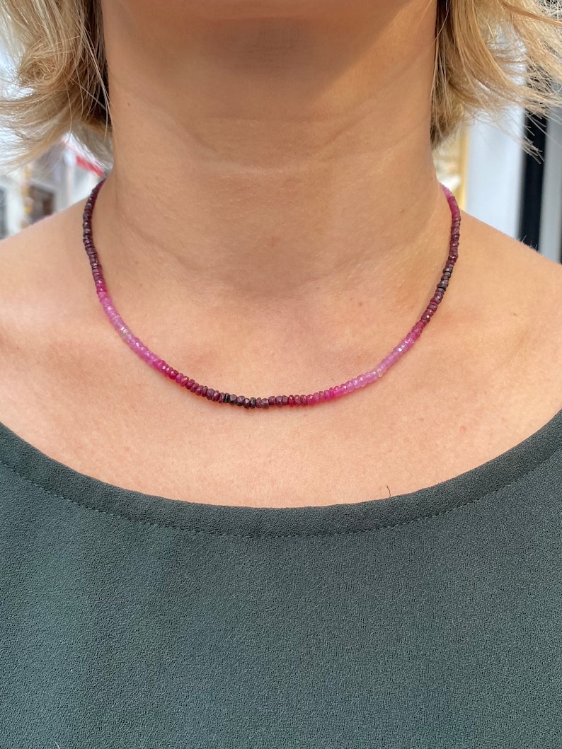 May include: A delicate necklace made of small, graduated pink and purple gemstones. The necklace is made of tiny beads that are strung together to create a gradient effect.
