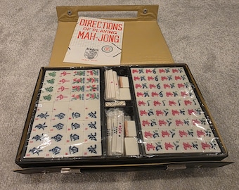 May include: A vintage Mah-Jong set in a black case with a tan handle and interior. The set includes tiles with Chinese characters and symbols, dice, and a booklet titled "Directions of Playing Mah-Jong."