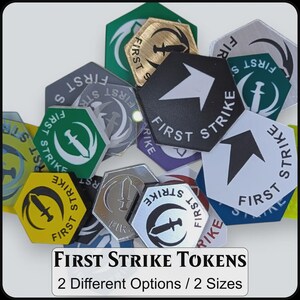 May include: A collection of hexagonal tokens in various colors including black, white, green, yellow, and metallic silver. Each token features the text FIRST STRIKE and a graphic of a sword or an arrow. The text FIRST STRIKE TOKENS 2 Different Options / 2 Sizes is printed at the bottom.