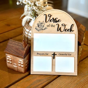 May include: Wooden sign with the words "Verse of the Week" and three blank spaces for writing. The top space is large and the bottom two spaces are smaller. The smaller spaces are labeled "Prayers for" and "Grateful for".