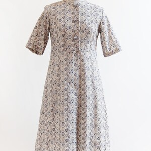 May include: A white dress with a blue floral pattern and a button-up front. The dress has short sleeves and a knee-length skirt.