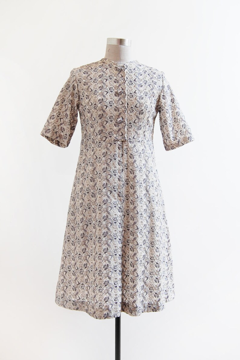 May include: A white dress with a blue floral pattern and a button-up front. The dress has short sleeves and a knee-length skirt.