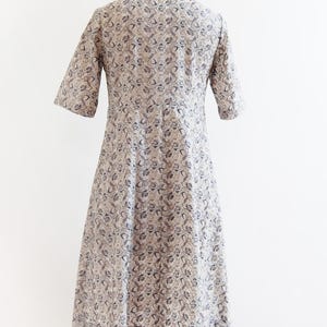 May include: A white dress with a black floral pattern. The dress has a round neckline and short sleeves. It is fitted at the waist and flares out to the hem.