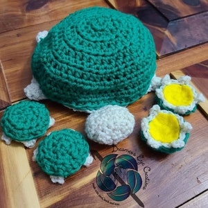 May include: Crocheted turtle toy set with a large green shell, four smaller green shells, and two white shells with yellow centers. The set is made with yarn and is suitable for children.