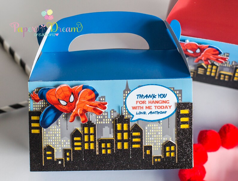 Puede incluir: Caja de regalo azul y roja con un dise&ntilde;o de personaje de Spiderman. La caja tiene un asa y dice "Gracias por celebrar conmigo hoy, Con cari&ntilde;o, Anthony".