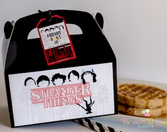 May include: Black and white Stranger Things party favor box with a red Stranger Things logo and a red tag that says "Friends Don't Lie" with a yellow sun graphic. The box is decorated with silhouettes of the characters from the show.