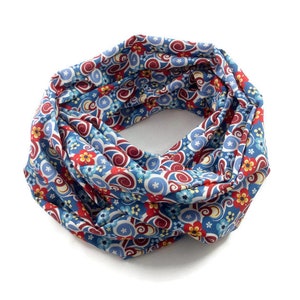 Könnte beinhalten: Ein blauer und roter gemusterter Infinity-Schal mit einem wirbelnden Design und kleinen floralen Akzenten.