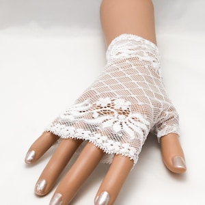 Puede incluir: Guantes sin dedos de encaje blanco con dise&ntilde;o floral. Los guantes est&aacute;n hechos de encaje delicado de tejido abierto. Cubren la mano hasta los nudillos, dejando los dedos expuestos.