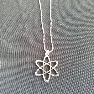 May include: A silver necklace with an atom pendant. The chain is made of small silver beads.