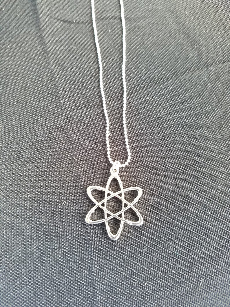 May include: A silver necklace with an atom pendant. The chain is made of small silver beads.