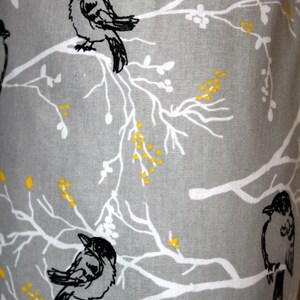 May include: Gray fabric with a white and yellow floral pattern and black silhouettes of birds perched on the branches.