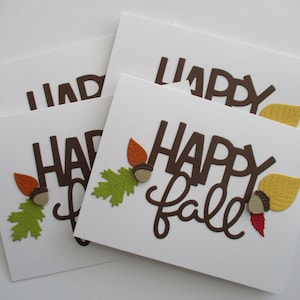 May include: White greeting cards with the words "HAPPY Fall" in brown lettering. Each card is decorated with fall-themed embellishments, including acorns, leaves, and a yellow leaf.