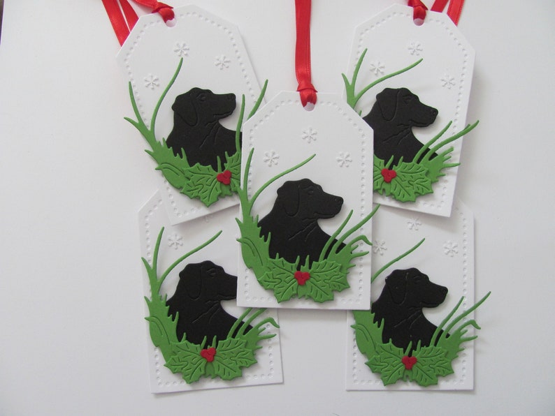 May include: Five white gift tags with black silhouette of a dog's head in green grass with red holly berries.