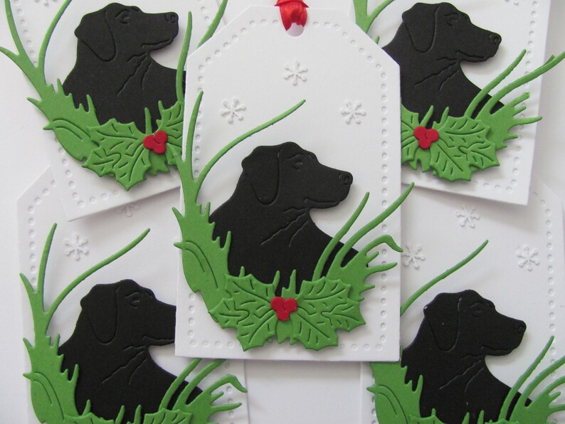 May include: Five white gift tags with black silhouettes of Labrador Retrievers, green holly leaves, and red berries. The tags are decorated with a white snowflake pattern.