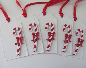 May include: Five white gift tags with red ribbon and a red and white candy cane design.