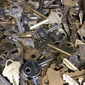 May include: A close-up shot of a collection of various metal keys. The keys are in different shapes and sizes, with some showing signs of wear. The keys are in shades of silver, gold, and bronze, with some having visible markings.