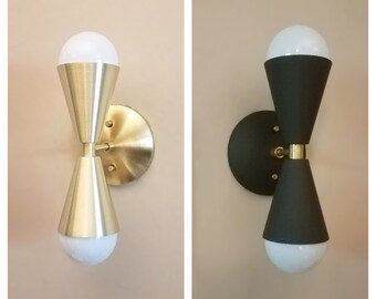 May include: Two wall sconces with a modern design. One sconce is gold with a white shade, and the other is black with a white shade.
