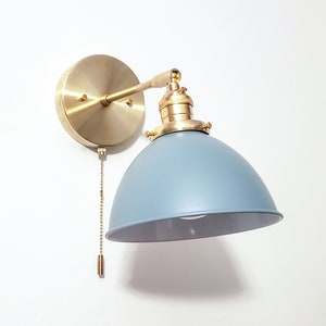 May include: A brass wall sconce with a blue metal shade. The sconce has a chain pull switch.