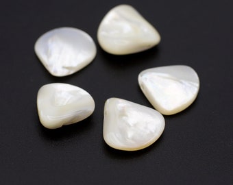 May include: Five pearlescent, off-white, teardrop-shaped shell pieces arranged on a black surface. The shells have a smooth, glossy finish with subtle iridescent highlights. The arrangement suggests a decorative or crafting theme.
