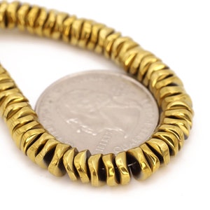 May include: A gold-toned hematite beaded bracelet with a coin for size reference.