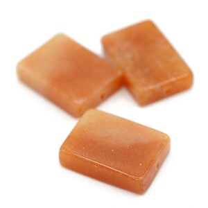 May include: Three rectangular orange carnelian gemstone beads with holes drilled through the center.