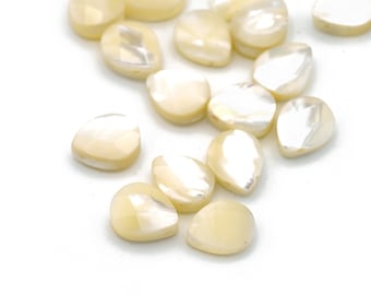May include: A collection of white pearlescent teardrop-shaped beads. The beads are smooth and have a subtle iridescent sheen.