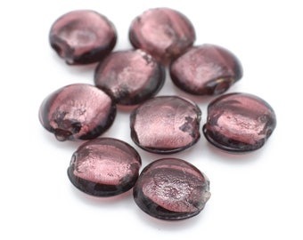 Op de afbeelding: Tien ronde, platte, paarse glazen kralen met een metallic glans. De kralen zijn verspreid over een witte achtergrond.