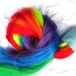 May include: A rainbow-colored ponytail hair extension with a light blue felt pouch attached to a silver key ring.