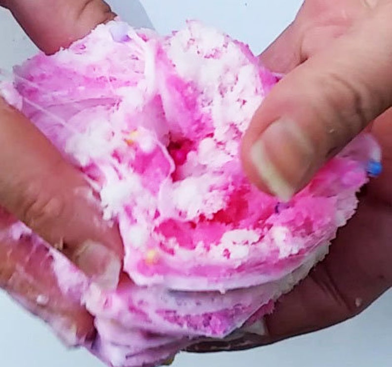 Puede incluir: Slime esponjoso rosa y blanco con chispas de colores. El slime est&aacute; siendo sostenido en dos manos.