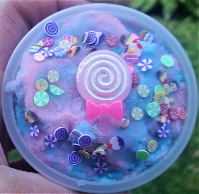 Peut inclure: Une slime bleue et rose avec une sucette rose et des vermicelles color&eacute;s. La slime est dans un r&eacute;cipient en plastique transparent.