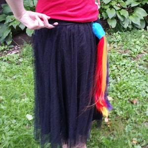 May include: A black tulle skirt with a rainbow colored ponytail attached to the back.