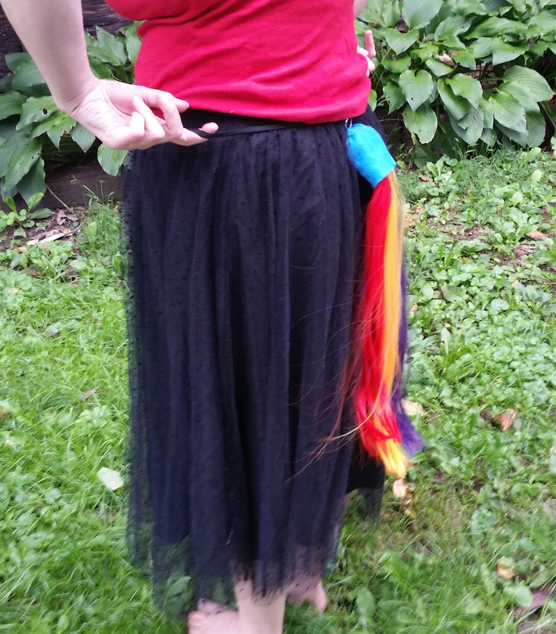 May include: A black tulle skirt with a rainbow colored ponytail attached to the back.