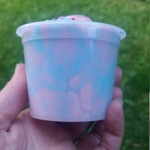 Peut inclure: Un r&eacute;cipient en plastique transparent rempli de slime rose et bleu en spirale. Le slime a un aspect marbr&eacute;.
