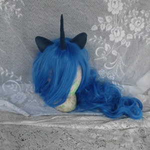 May include: Blue wig with a black unicorn horn and ears. The wig is on a white mannequin head.