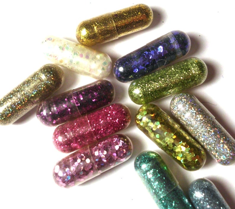 May include: Assortment of colorful glitter filled capsules. The capsules are clear and filled with various colors of glitter, including gold, silver, pink, blue, green, and purple.