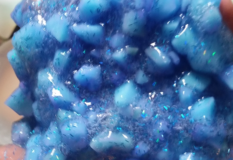 Puede incluir: Primer plano de slime azul con purpurina iridiscente. La slime est&aacute; llena de peque&ntilde;as piezas azules transl&uacute;cidas.