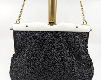 May include: A black crocheted evening bag with a white plastic frame and a gold chain strap.