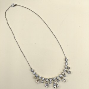 Puede incluir: Un collar de cadena de plata con un colgante de cristal en forma de l&aacute;grima. El colgante est&aacute; rodeado de cristales m&aacute;s peque&ntilde;os.