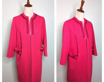May include: A long, pink, open-front jacket with a dark pink trim around the collar and pockets. The jacket is on a white mannequin.