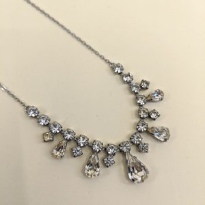 Puede incluir: Un collar de cadena de plata con un colgante de cristal en forma de l&aacute;grima. El colgante est&aacute; rodeado de cristales m&aacute;s peque&ntilde;os.
