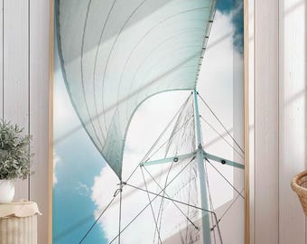 May include: A framed wall art print featuring a low-angle view of a sailboat mast and white sail against a bright blue sky with soft white clouds. The composition highlights the geometric lines of the rigging and the curve of the sail fabric.