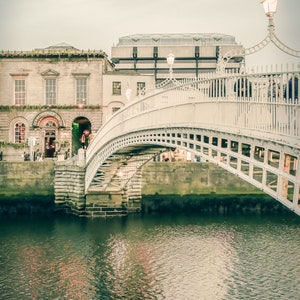 Photography print of Ha'penny Bridge in Dublin Ireland.  Shows water underneath with Merchant's bar in background.  Colors are muted green and beige.