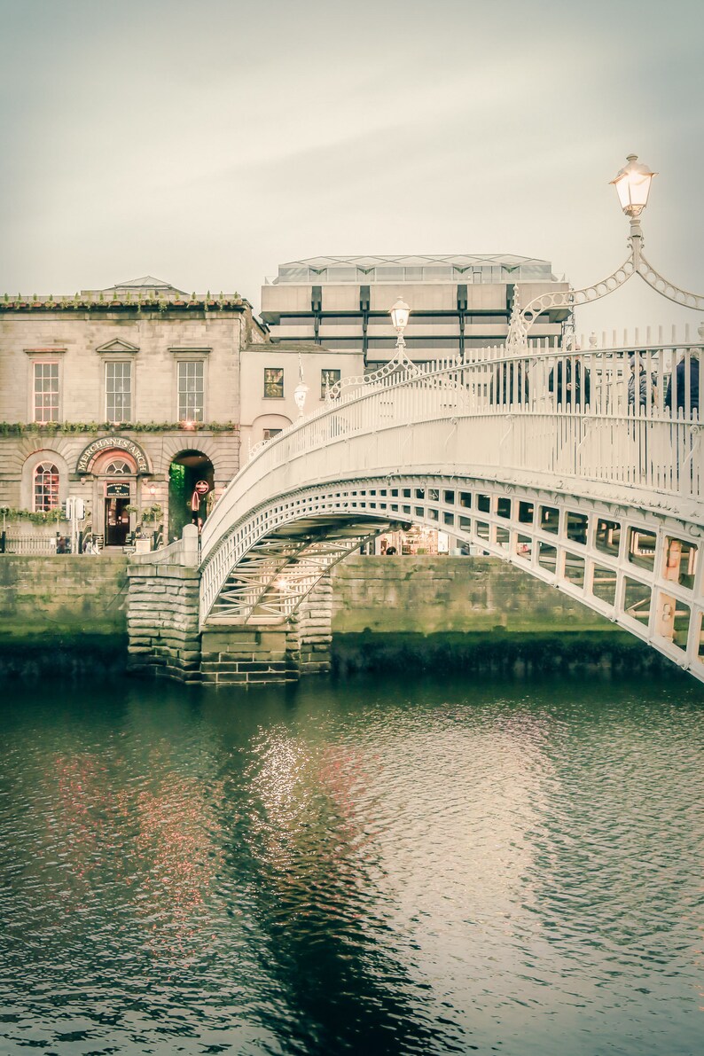 Photography print of Ha'penny Bridge in Dublin Ireland.  Shows water underneath with Merchant's bar in background.  Colors are muted green and beige.