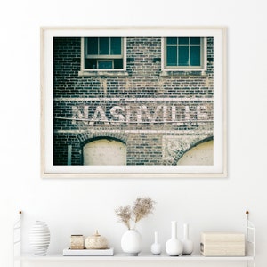 Nashville Photo Print shown framed (comes unframed).  It has soft, muted colors of blue and gray.  Features the city's name on an old brick building.