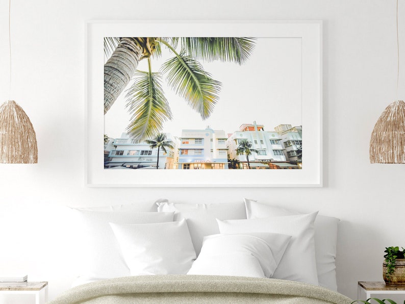 South Beach photography print showing 3 Art Deco hotels framed under a palm tree on the top left.  Soft pastel colors.